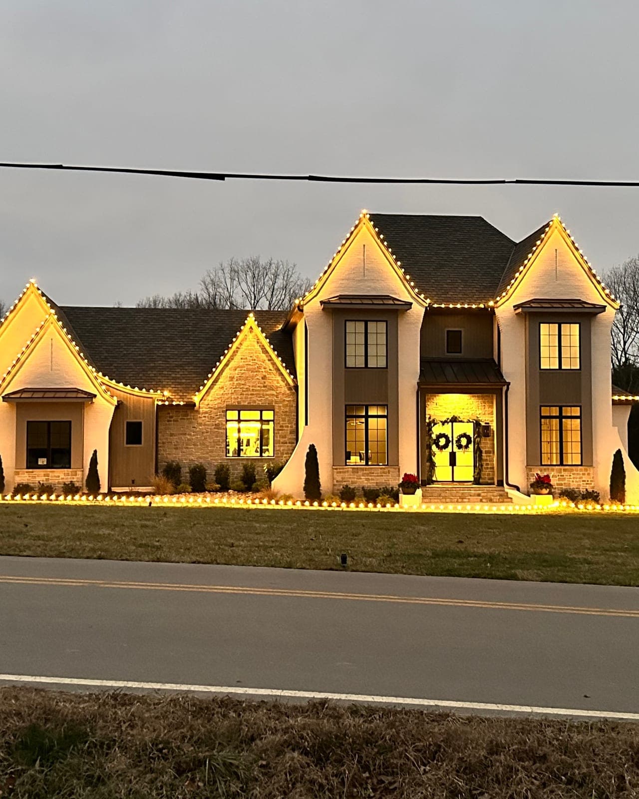 Home with Christmas lights: roofline, gable and ground lights at dusk